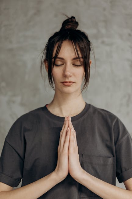 A serene woman with closed eyes practicing a simple meditative pose in a light-filled room